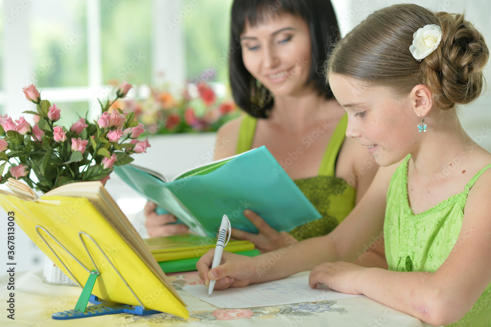 Cute girl and mother doing homework at home Cute girl and mother doing homework at home