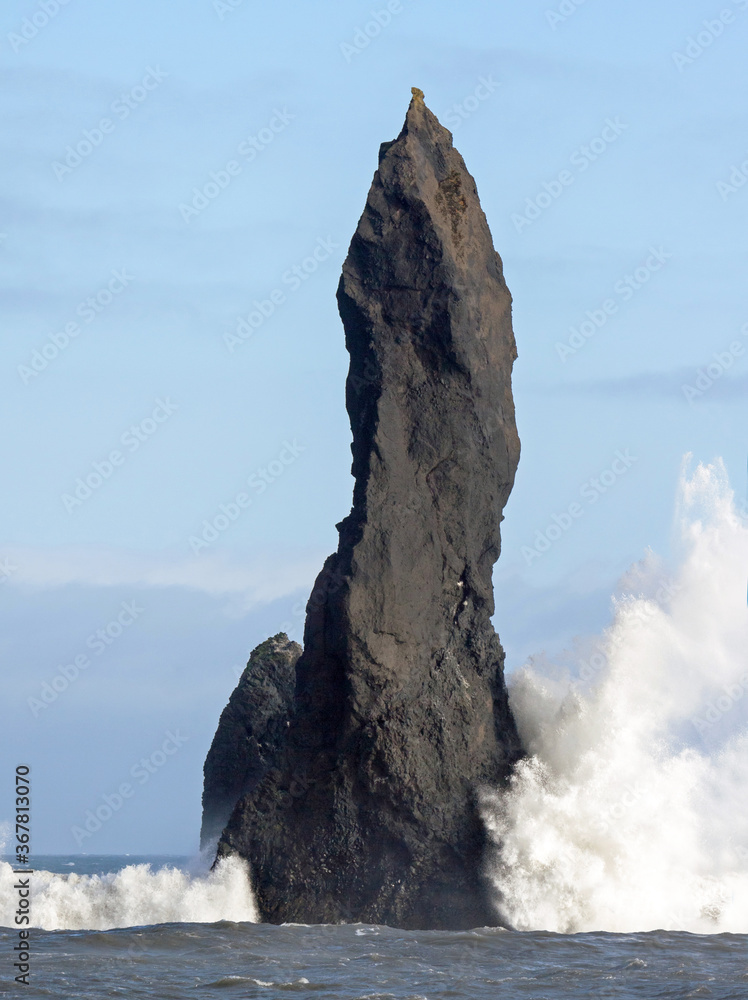 Black basalt sea stacks of Reynisdrangur at Reynisfjara beach, near Vik, Southern Iceland, with strong wind.