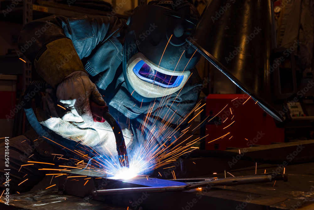 worker with protective mask welding metal and sparks worker with protective mask welding metal and sparks