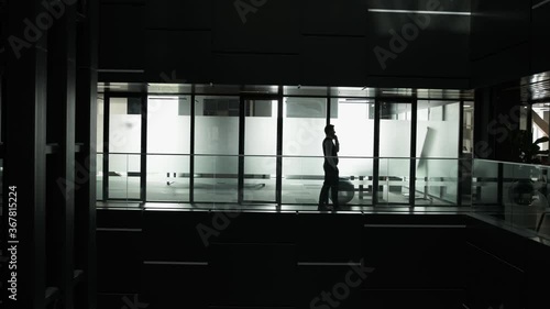 Silhouette of an young man that is talking at phone and walking inside the business building