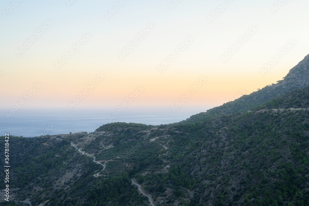 Obraz premium dusk mountain landscape with views of the Mediterranean sea and cloudless sky. Golden hour, haze or fog