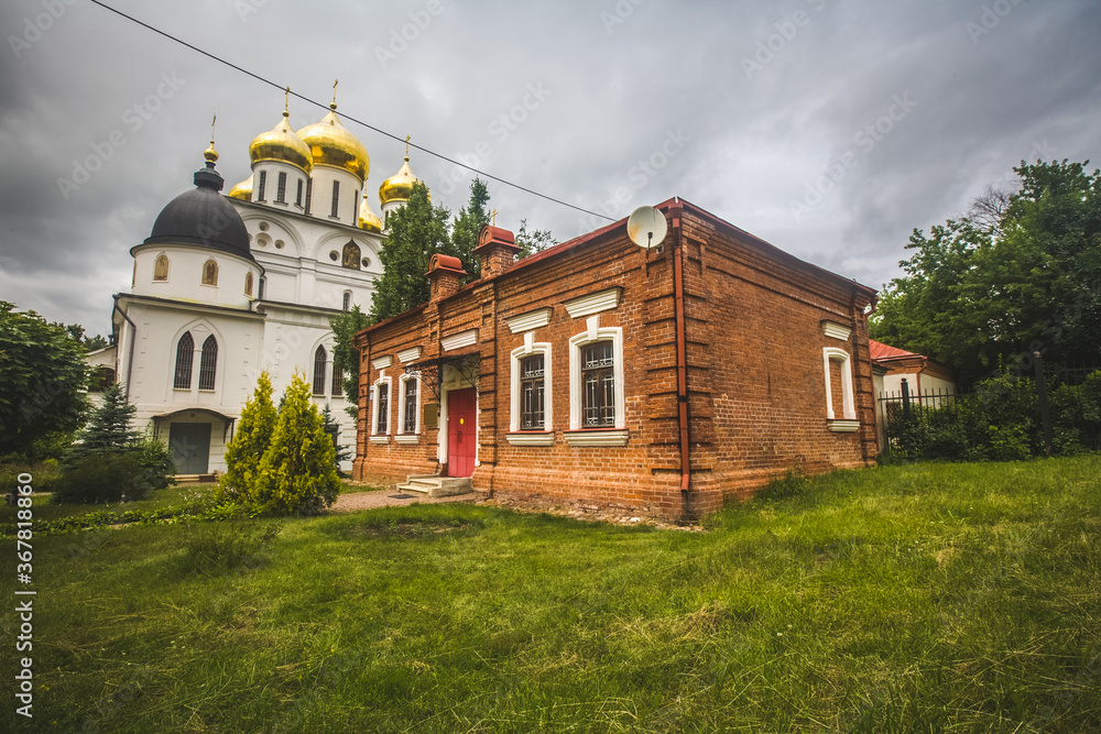 Fototapeta premium brick one-story house on a green lawn. Assumption Cathedral of the early 16th century in the city of Dmitrov, Russia. Orthodox church in the Dmitrov Kremlin.