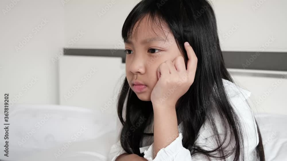 Asian child girl wearing a white shirt is contemplating or worried about something Asian child girl wearing a white shirt is contemplating or worried about something
