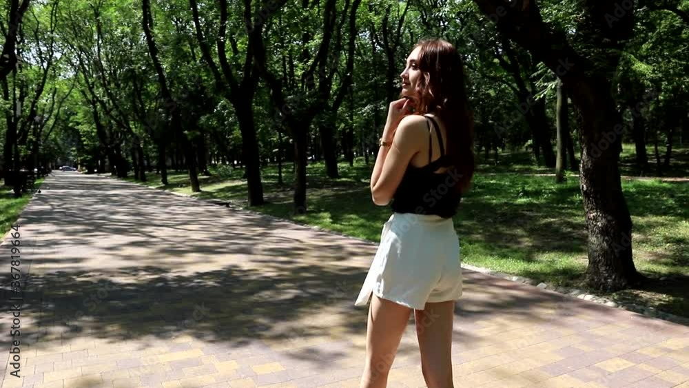 Cute redheaded teen girl strolls through a summer public Park Cute redheaded teen girl strolls through a summer public Park