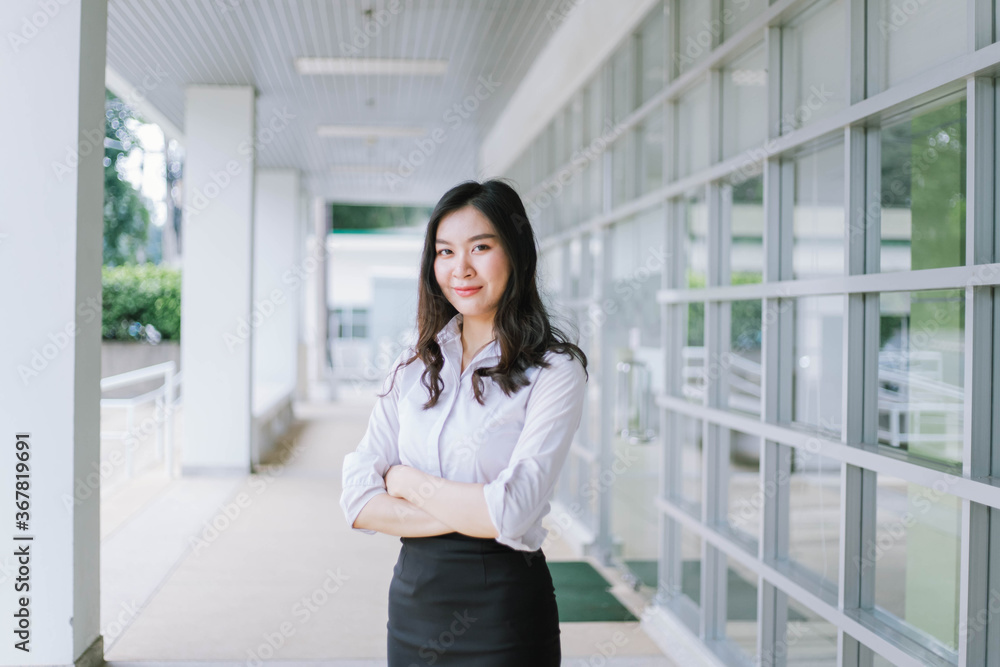 A smiling Asian business woman in white shirt crossed her arms