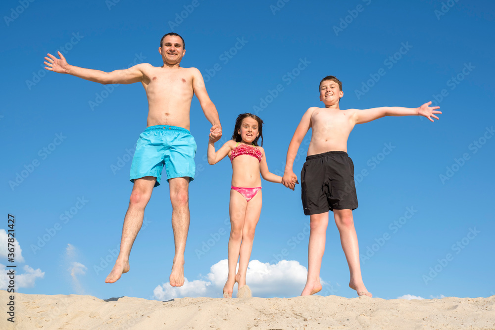 Happy family playing on the sand posing for the camera. Family games on vacation. Active rest, lifestyle. Happy family playing on the sand posing for the camera. Family games on vacation. Active rest, lifestyle.
