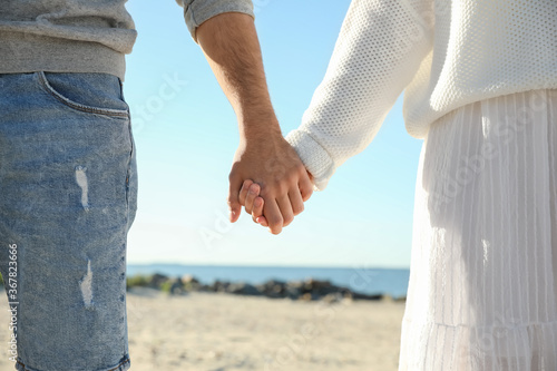 Young couple holding hands on beach, closeup. Honeymoon trip