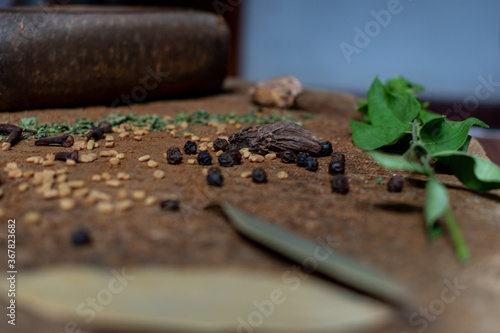 Indian Garam masala powder in bowl and it s ingredients colourful spices. Served over moody background. selective focus