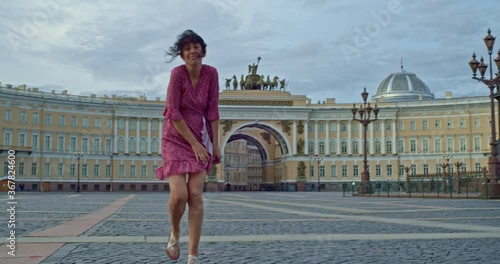 beautiful girl alone dances and smiles on Palace Square near the Hermitage in Saint Petersburg photo