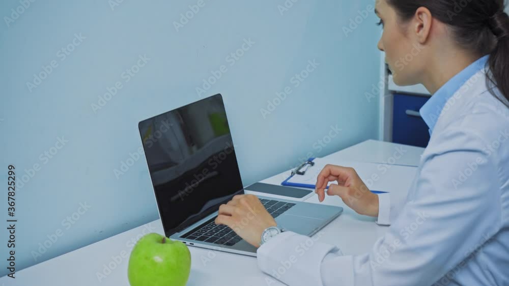 Dentist using laptop and talking on smartphone in clinic
