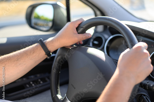 The man is driving. Men's hands hold the steering wheel of the car. Selective focus. © Anna Belova