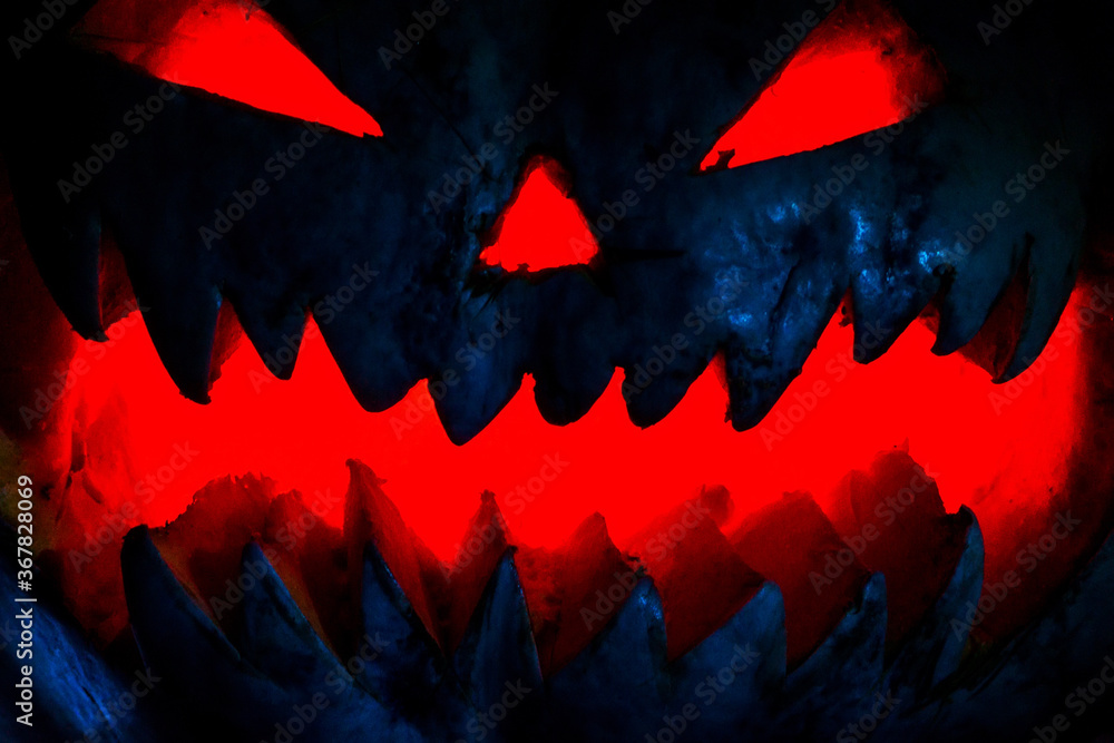 Fototapeta premium Scary smiling Halloween pumpkin on dark background. retro style, noise, selective focus