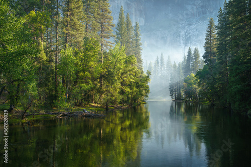 sunbeams on a foggy morning over merced river in yosemite national park