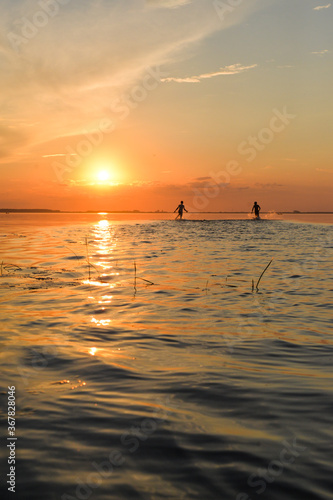 2 young boys running on the lake on sunset time © Anastasiia