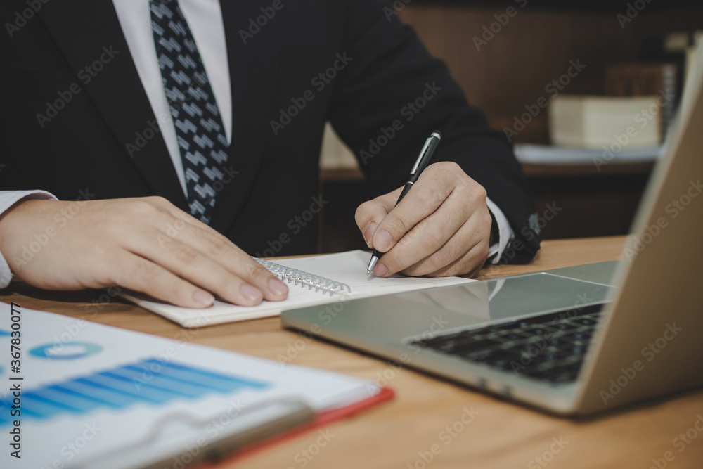 attractive business man in black suit working and writing on document report on desk in meeting room at home office, investment, contract, digital online marketing and financial business concept attractive business man in black suit working and writing on document report on desk in meeting room at home office, investment, contract, digital online marketing and financial business concept