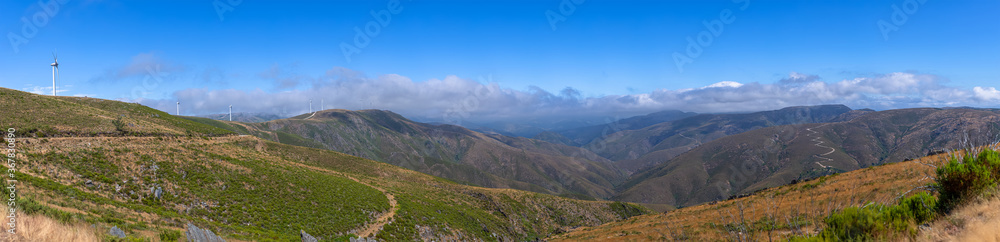 Ultra panoramic view at the Pisao mountains, with wind turbines and blue sky as background