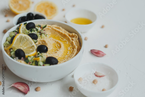 Fototapeta Naklejka Na Ścianę i Meble -  Hummus with olive oil, olives, lemon, garlic, sesame seeds, onions and cucumbers.
