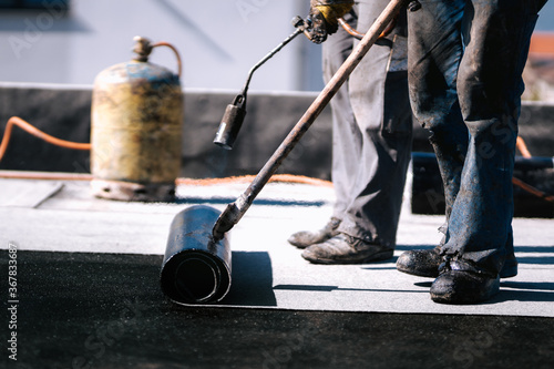 Waterproofing insulation with bituminous membrane system. Professional workers waterproofing house construction site.
