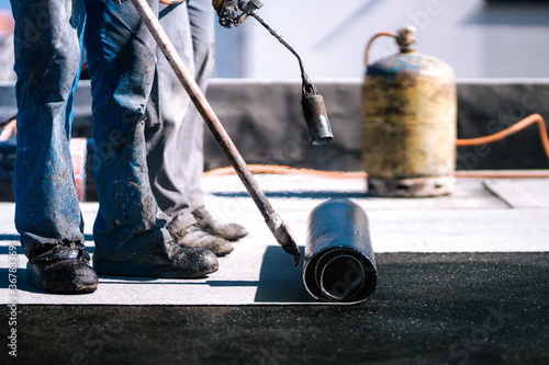 Waterproofing insulation with bituminous membrane system. Professional workers waterproofing house construction site