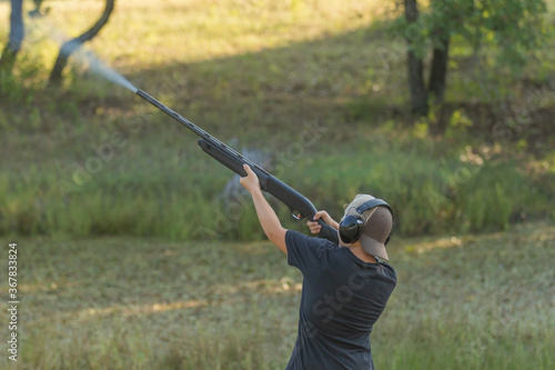 young boy wearing ear protection shooting a shotgun 