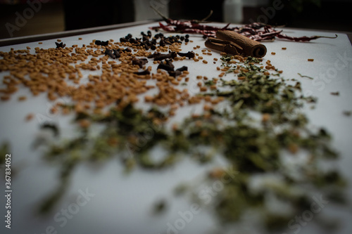 Indian Garam masala powder in bowl and it's ingredients colourful spices. Served over moody background. selective focus