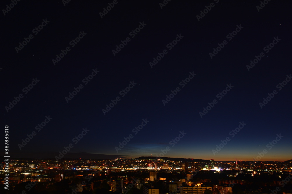 Fototapeta premium Panorama of Zurich at night with twilight in the sky as seen from Triemli 