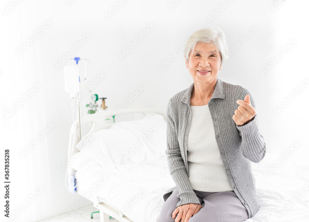 old asian patient sitting on bed, she feeling happy and smile, she show mini heart sign with hand in hospital, elderly healthcare old asian patient sitting on bed, she feeling happy and smile, she show mini heart sign with hand in hospital, elderly healthcare