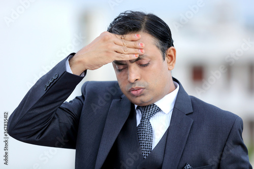 Worried Indian businessman. Young executive in severe tension. Headache. Shocked from bad news.