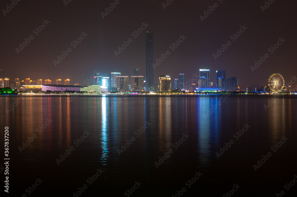 Suzhou city viewed from the lake with colorful lights reflecting in the water.