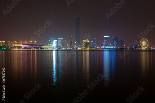 Suzhou city viewed from the lake with colorful lights reflecting in the water.