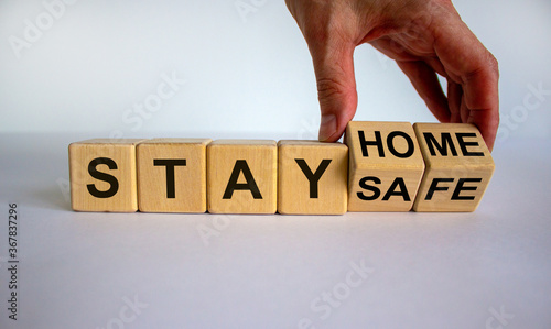 Wallpaper Mural Wooden cube form the expression 'stay home, stay safe'. Male hand. Beautiful white background, copy space. Concept. Torontodigital.ca
