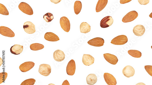 Almond and peeled hazelnuts falling around copy space, isolated on white