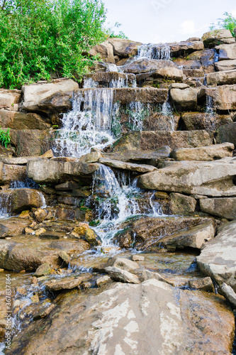 River waterfall. Small jets of water flow down the stones on a sunny day