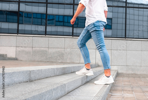 Canvastavla Man with blue geans and white sneaker shoes in stair, go up