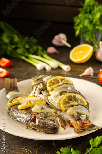 Baked carassius with lemon and spices in foil in the oven, cooked river fish crucian carp photo