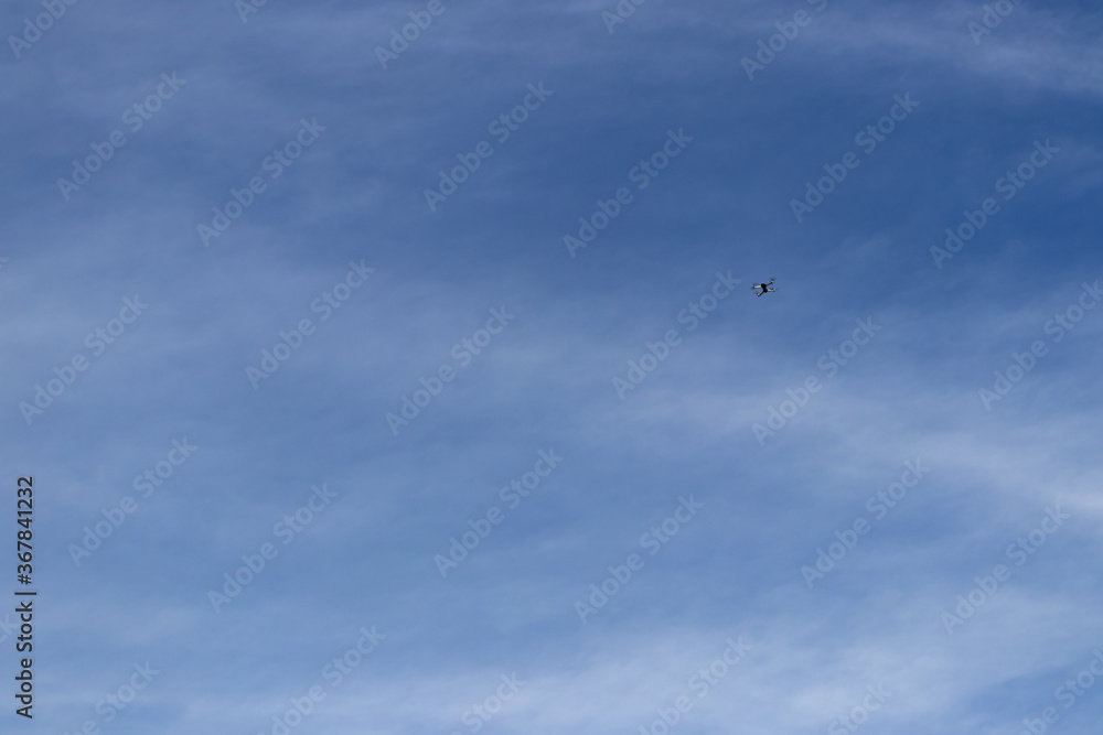 Barely seen drone hovering high on the blue sky. Barely seen drone hovering high on the blue sky.