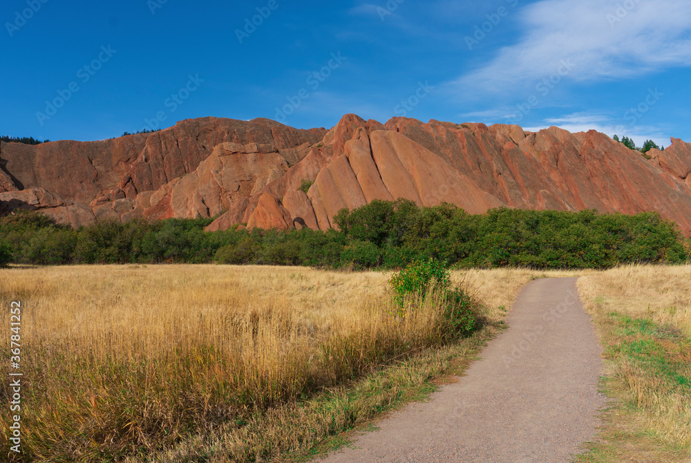 Dirt Walking Path in Park Through Golden Meadow Leading to Red Rock Formations