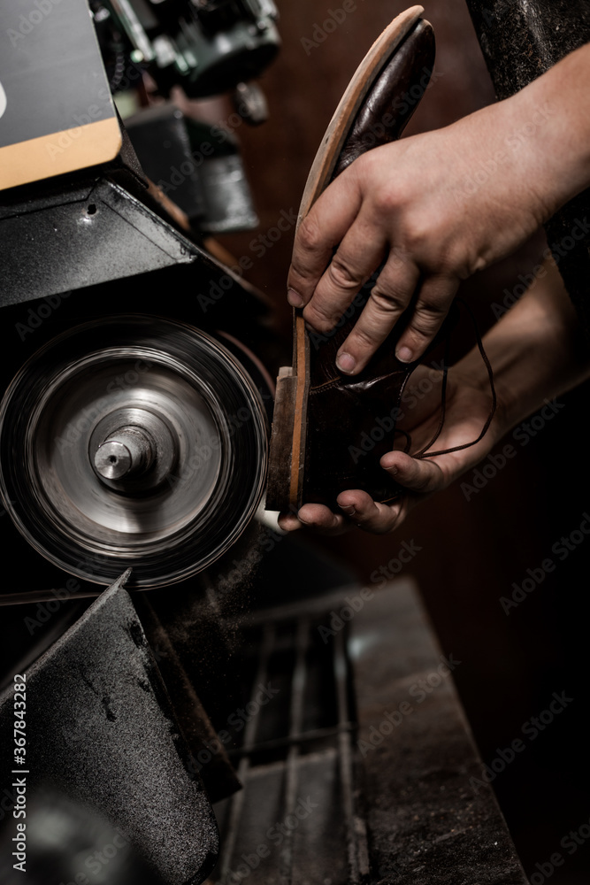 Male shoemaker repairing heel of shoe on grinding machine. Cobbler at work. Male shoemaker repairing heel of shoe on grinding machine. Cobbler at work.
