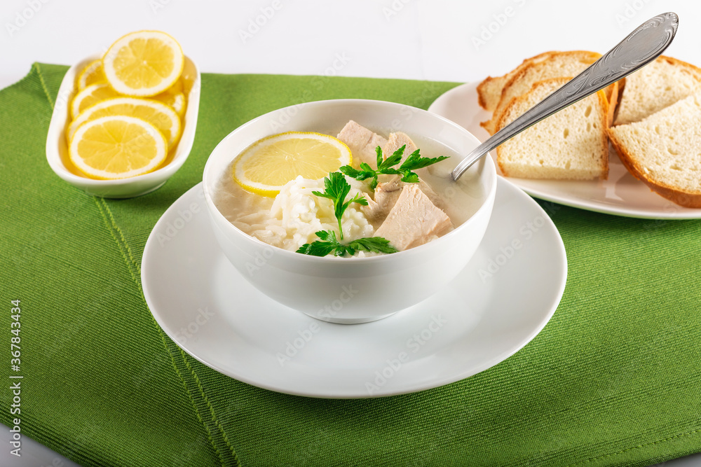 Chicken soup with lemon, egg yolks, parsley and rice. High key. Green background. Chicken soup with lemon, egg yolks, parsley and rice. High key. Green background.