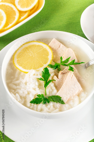 Chicken soup with lemon, egg yolks, parsley and rice. High key. Green background.