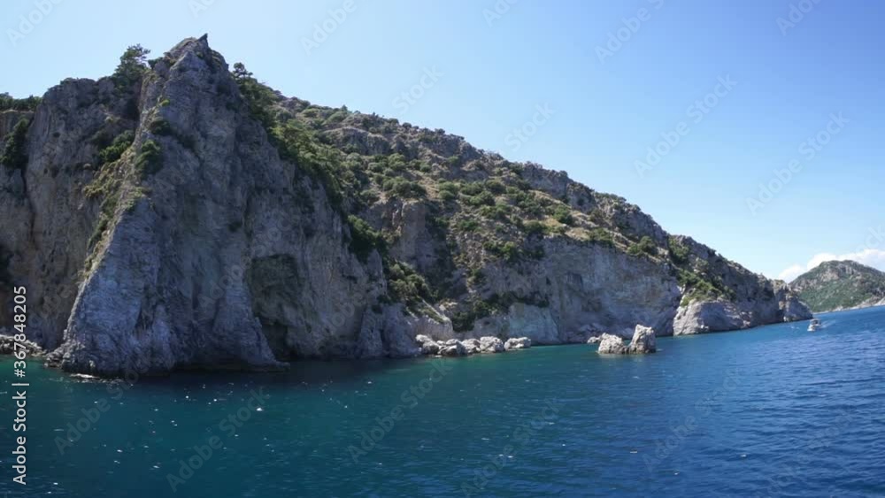 A rocky seashore and a white boat floats on the waves. A rocky seashore and a white boat floats on the waves.