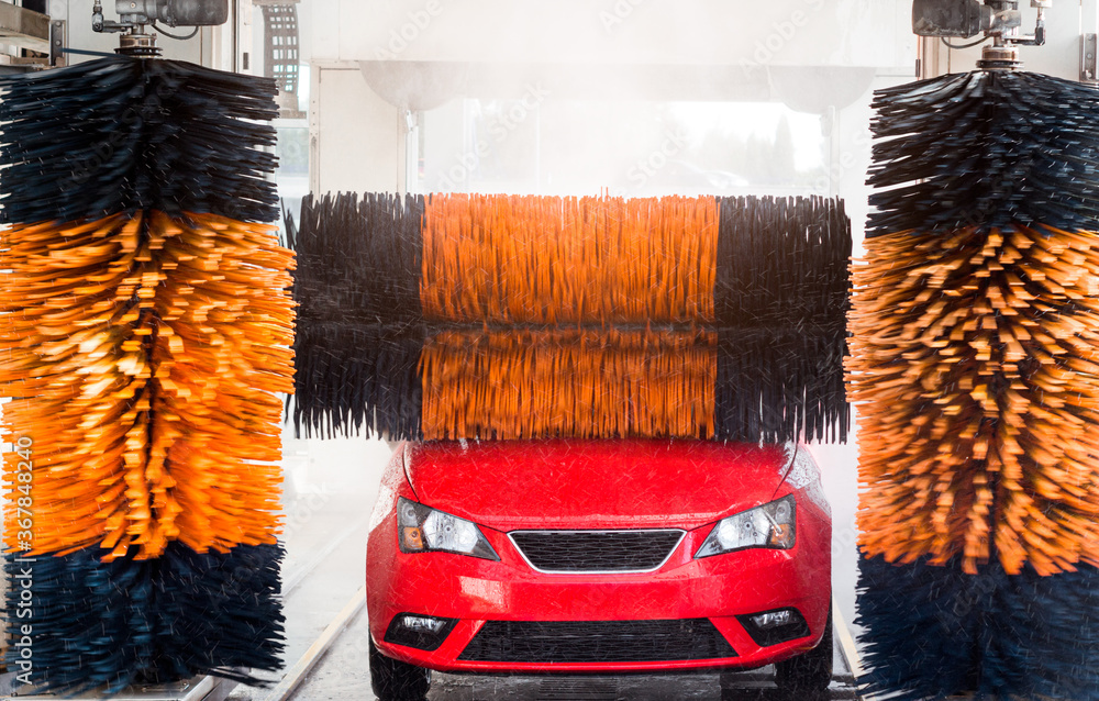 Car wash, red car in automatic car wash, yellow and blue brush. Stock