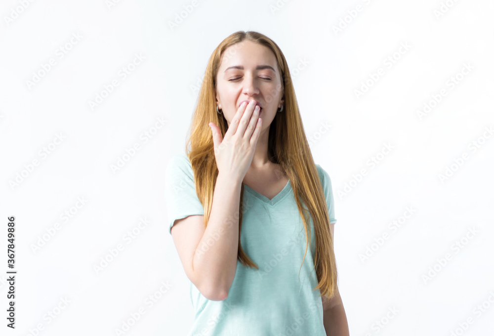 Tired girl on a white background yawning covers her mouth with her palm Tired girl on a white background yawning covers her mouth with her palm