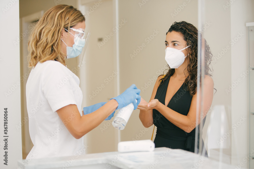 person putting on hand sanitizer to prevent infection with coropnavirus or covid19. She is entering a beauty clinic person putting on hand sanitizer to prevent infection with coropnavirus or covid19. She is entering a beauty clinic
