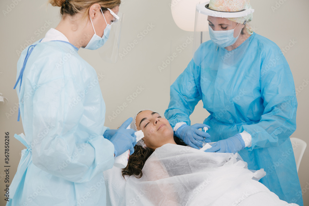 person in beauty center doing a treatment during in cororavirus or covid-19. The doctor wears a protective mask to prevent infection and ensure safety person in beauty center doing a treatment during in cororavirus or covid-19. The doctor wears a protective mask to prevent infection and ensure safety