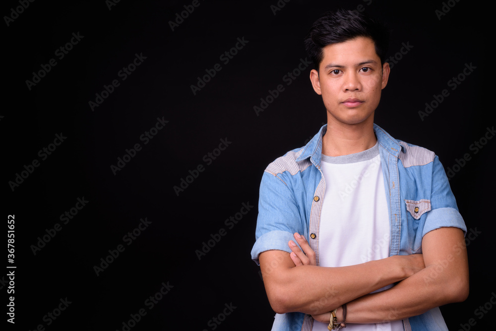 Portrait of young Asian man against black background Portrait of young Asian man against black background