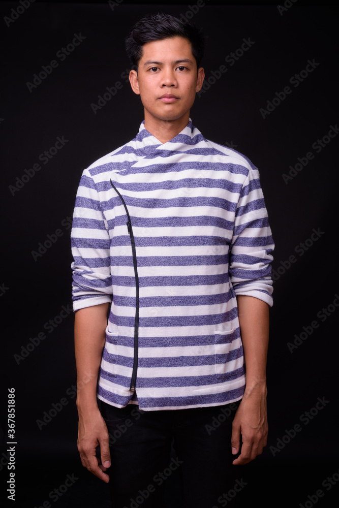 Portrait of young Asian man against black background Portrait of young Asian man against black background