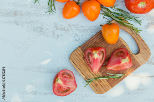 Various colorful tomatoes and rosemary herb on light background
