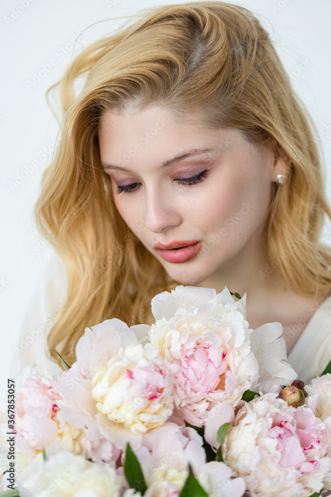 Indoor shot of beautiful girl holding white and rose peonies, winsome woman with big bouquet, enjoying her flowers