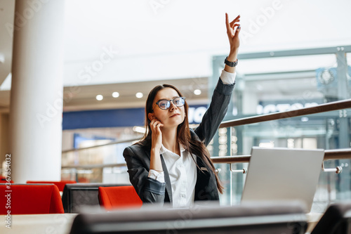 A woman calls a colleague, waves her hand for a meeting. Girl works on a laptop in the workplace. Successful business woman creates a startup and makes decisions.